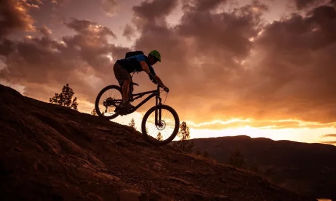 Ciclista descendo morro ao anoitecer