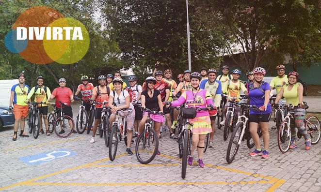 Grupo de ciclistas com várias pessoas com suas respectivas bicicletas em área urbana, todos utilizando trajes adequados para o ciclismo
