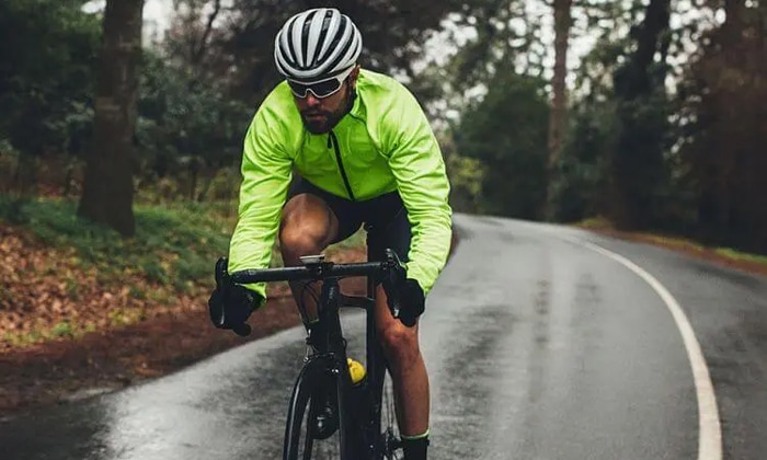Homem pedalando utilizando um corta-vento na cor verde limão