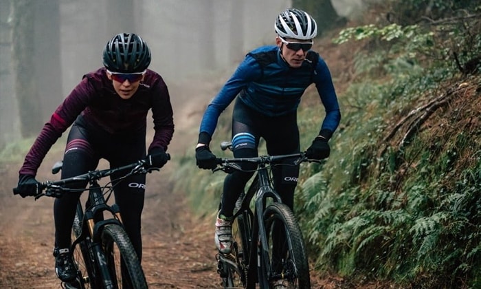 Casal andando de bike com blusa e luvas