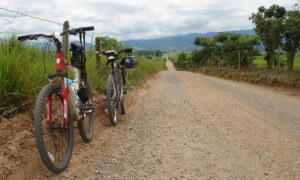 Estrada rural com duas bicicletas estacionadas, uma vermelha e outra preta
