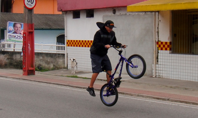 pessoa vestida de preto empinando bicicleta em rua