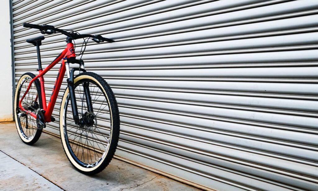 Bicicleta Mountain Bike KOG vermelha encostada no portão