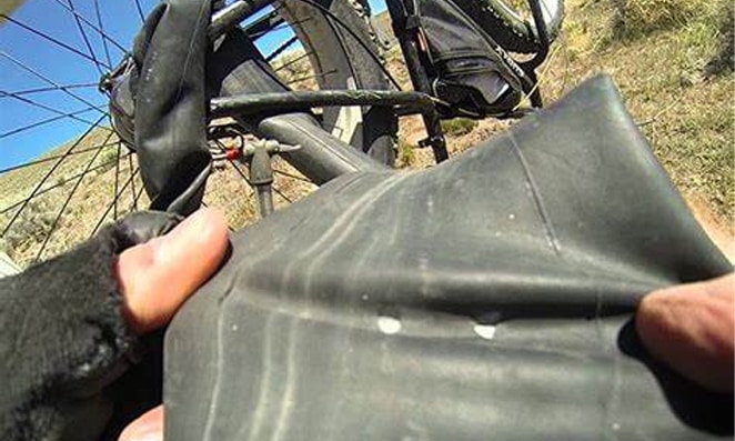 Pessoa esticando câmara de ar de bicicleta e procurando furo