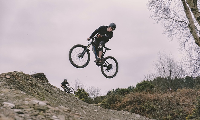 Homem pulando de uma vale para outro em uma trilha