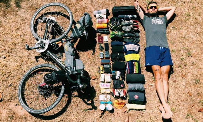 Homem com sua bicicleta e todos os acessórios e roupas necessários para pero