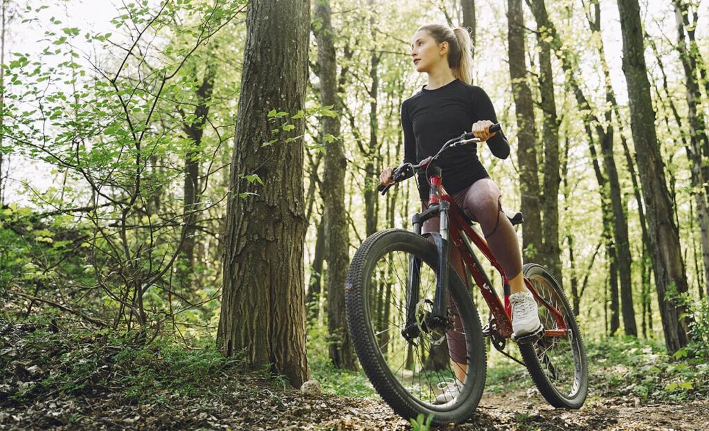 Mulher de bike pedalando em uma trilha