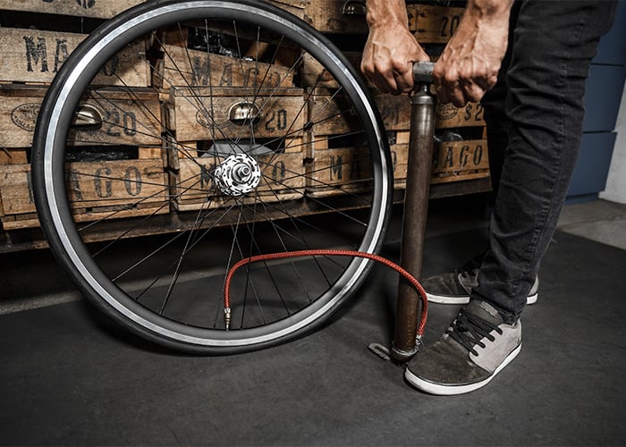 Pneu de uma bike sendo enchido por uma bomba de chão