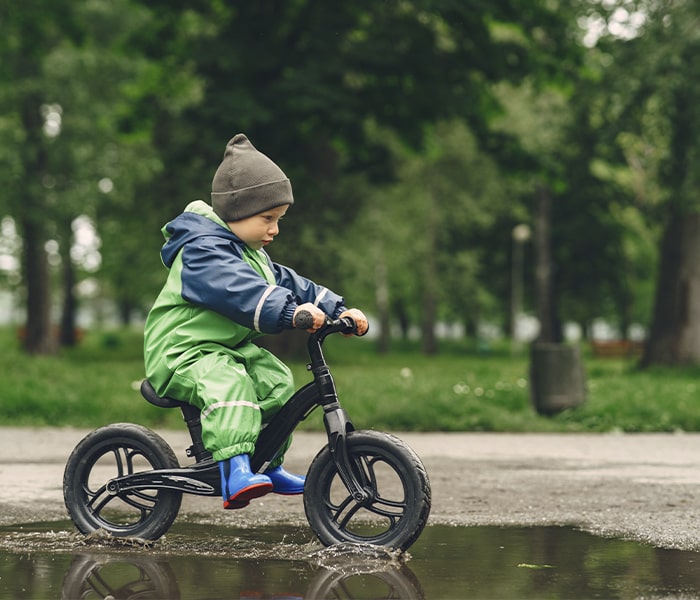 Criança com roupa de frio andando de bike com rodinha