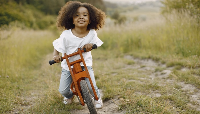 Menina andando de bicicleta de madeira